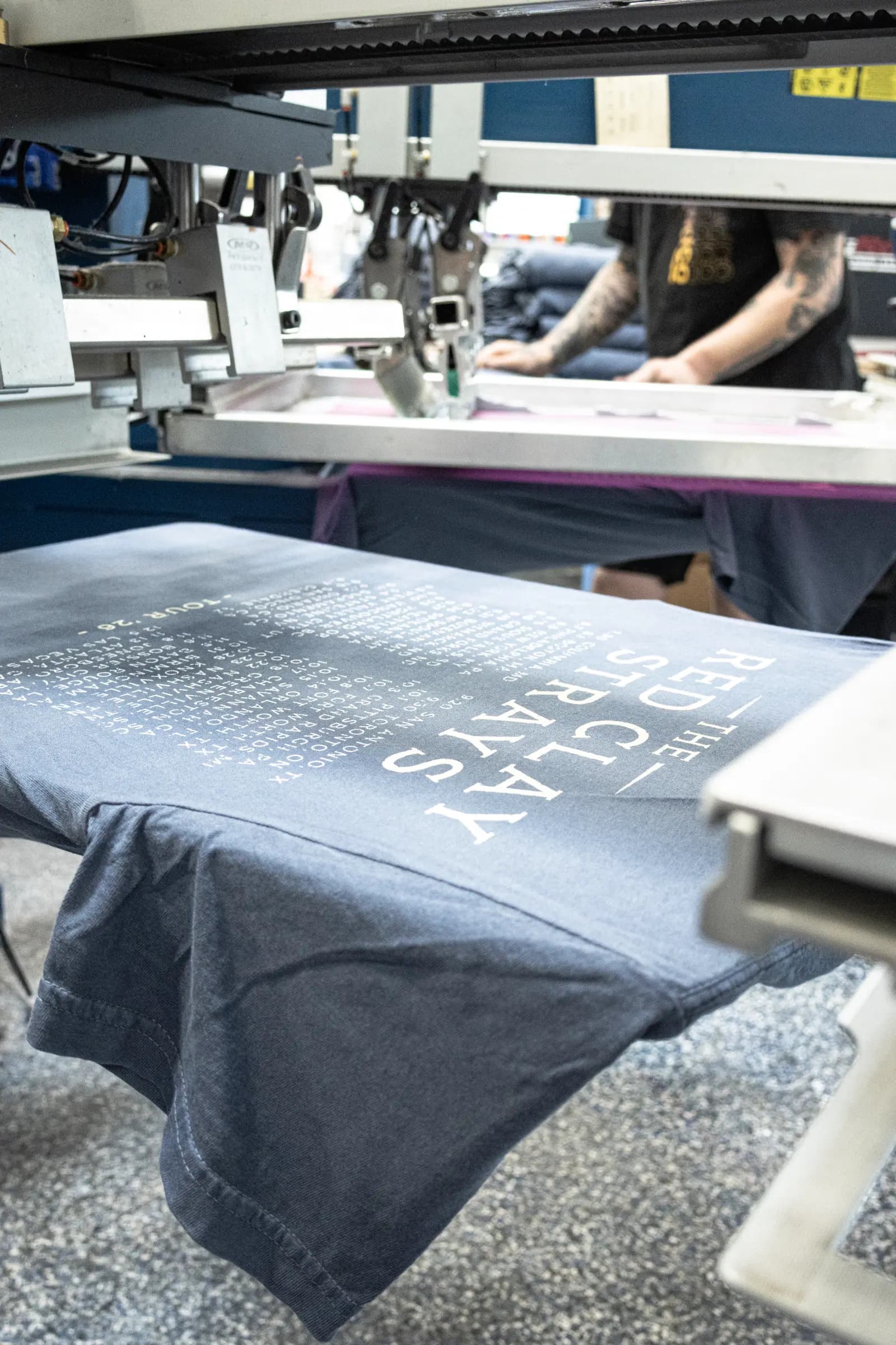 A shirt printed with long lines of fine text, still on the press