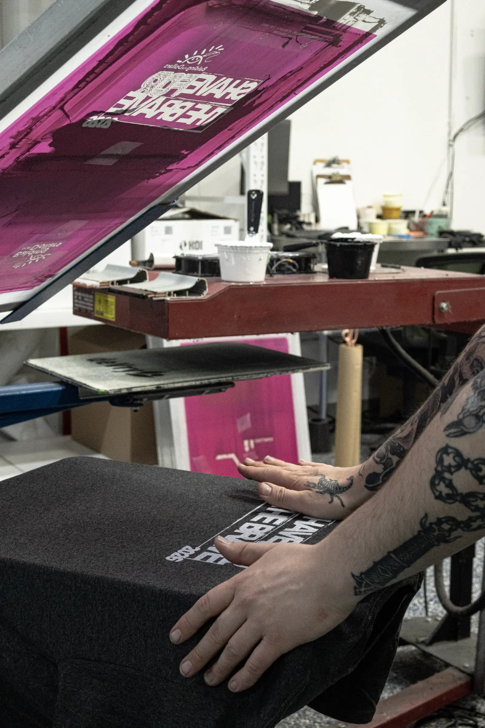 A printer smoothing a shirt onto the pallet of a manual screen-printing press