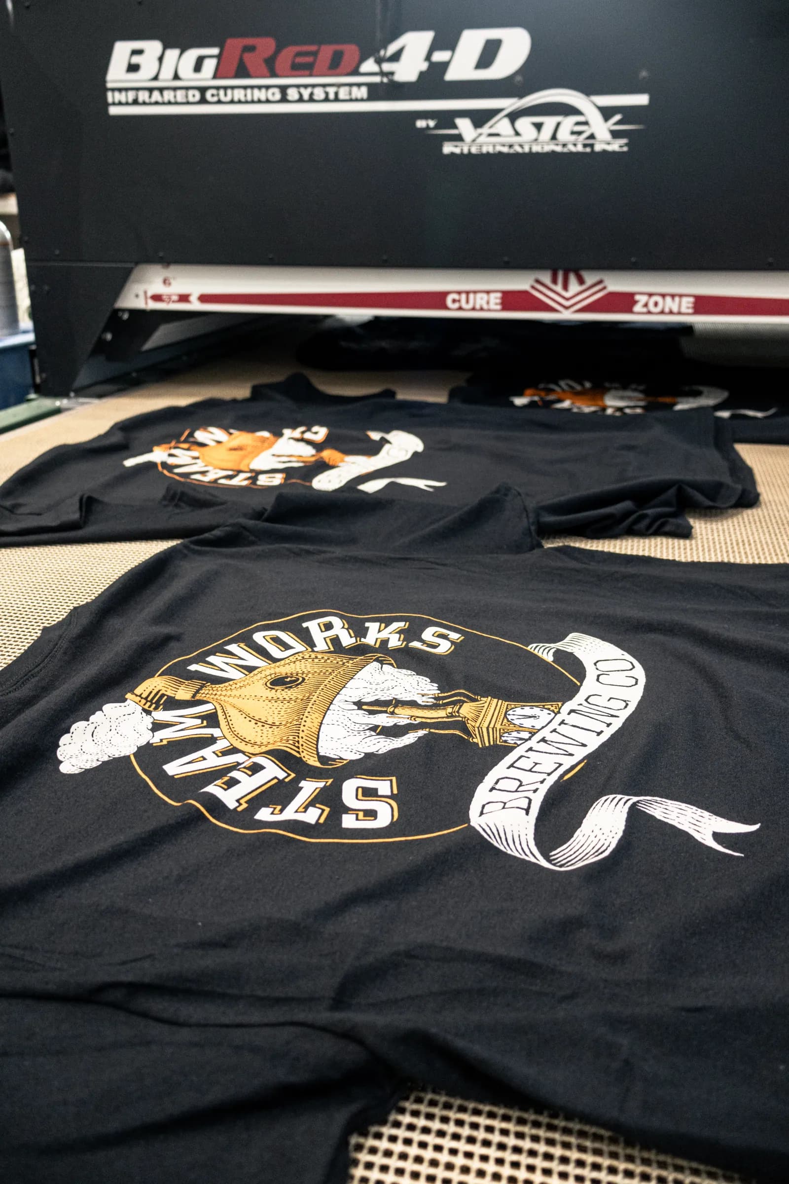 Screen-printed shirts leaving the infrared dryer at ThreadCo Print Shop