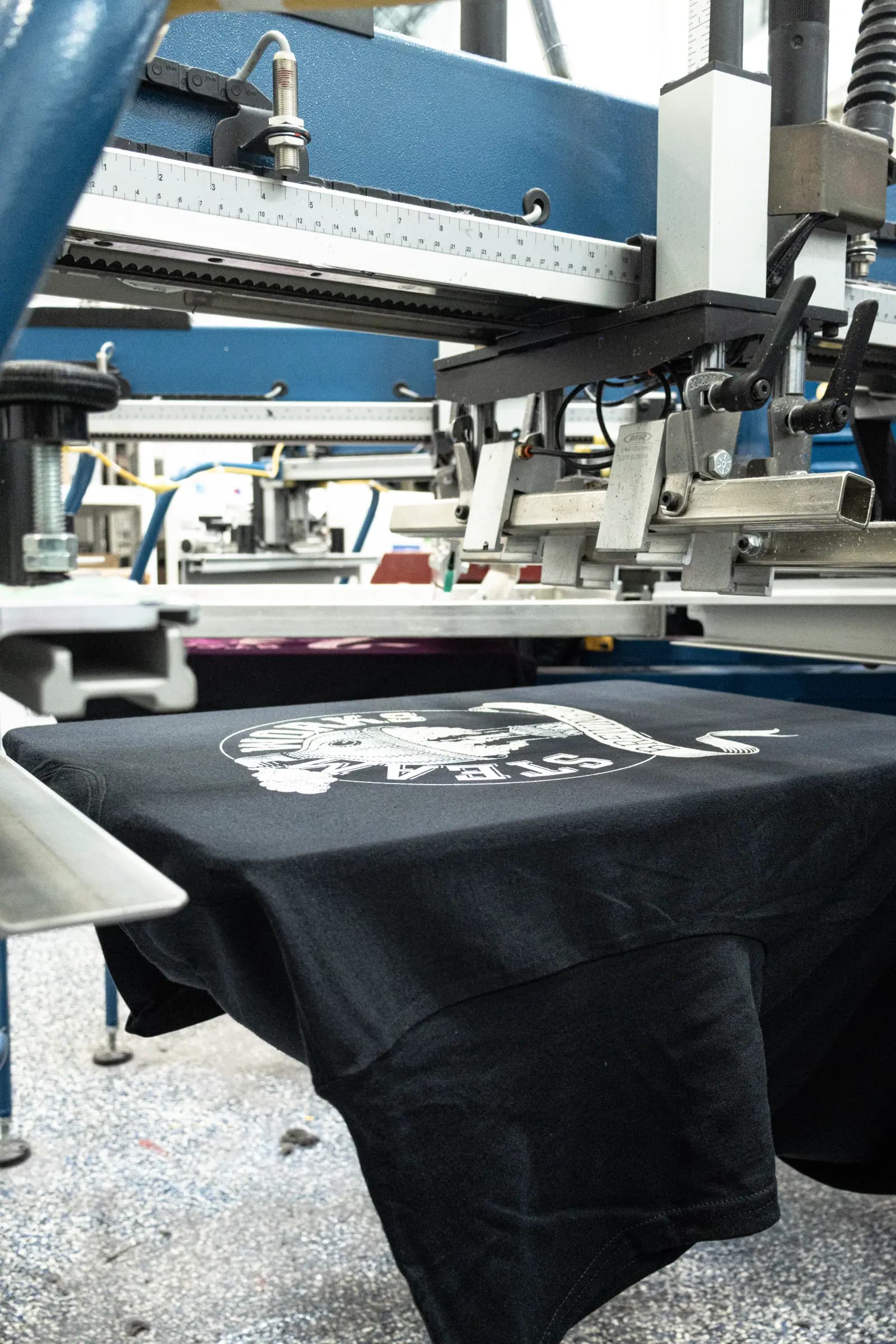 A black shirt on the press with the white first layer of a print